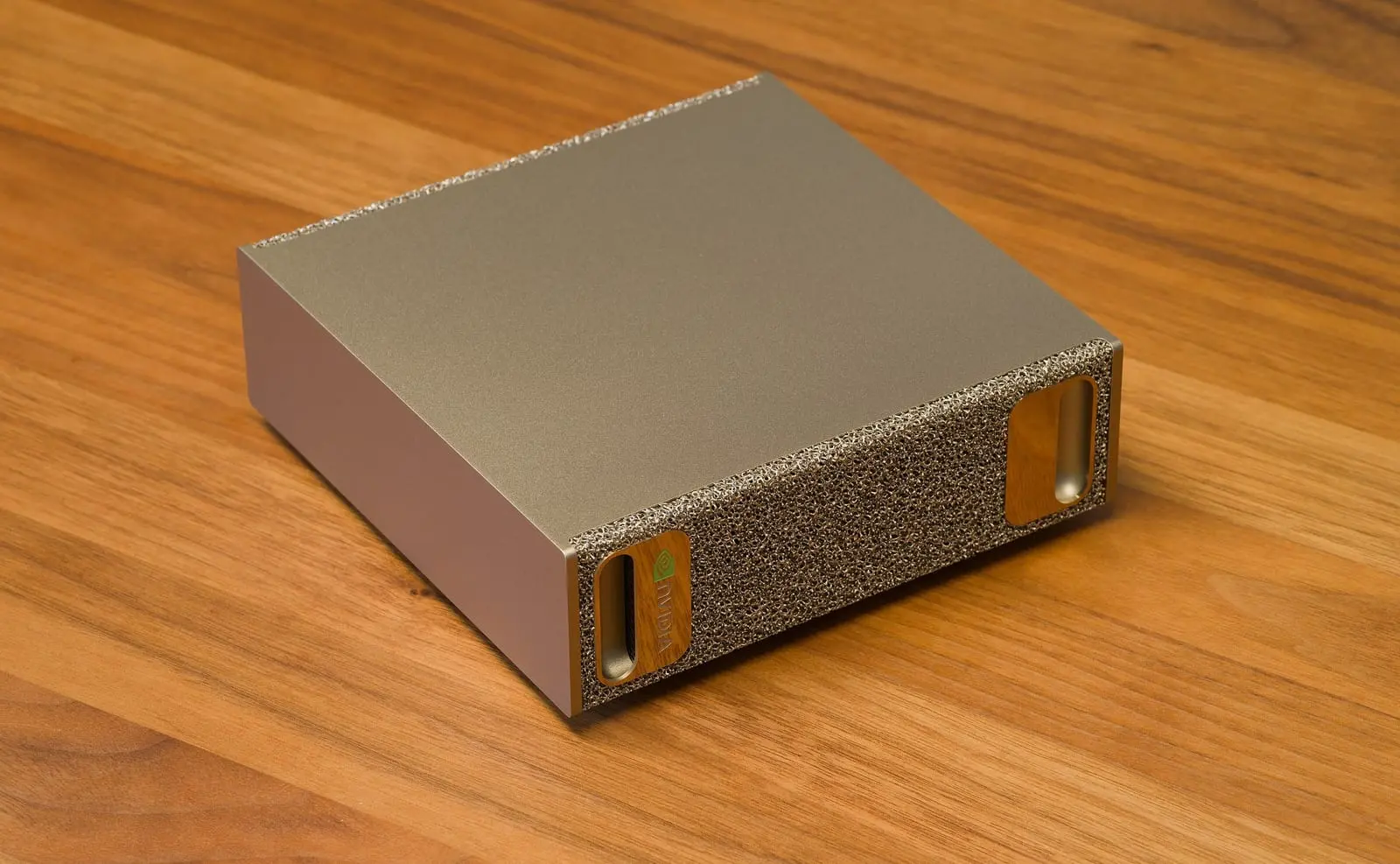 An NVIDIA DGX Spark desktop computer with a gold metal-foam front panel on a wooden table.